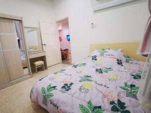巴特沃思Bagan Terrace House near to Sunway Carnival Mall, Seberang Jaya的一间卧室配有一张带粉红色和绿色棉被的床