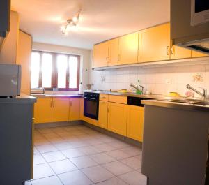 AyentMayen2003 Ayent Anzère的厨房配有黄色橱柜和瓷砖地板。