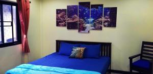 高兰Tonmai Aquablue的一间卧室配有一张蓝色的床,墙上挂有四幅画作