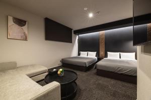 福冈GRAND BASE Hakata Premium的酒店客房,设有两张床和一张沙发