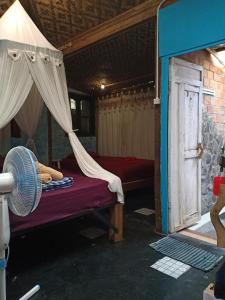 日惹阿朱那花园民宿的客房配有带蚊帐的床和风扇。