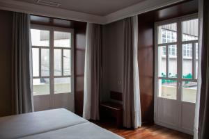 费罗尔Hotel Alda El Suizo的一间卧室设有一张床和两个大窗户