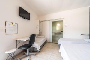 索罗卡巴Hotel Campolim的客房设有两张床、一张桌子和一把椅子。