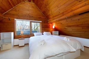二世古二世古小屋酒店的木制客房内的一间卧室配有一张白色大床