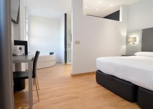 阿尔考本达斯阿尔库本达斯UVE酒店的一间带一张床和一张书桌的卧室以及一间浴室。