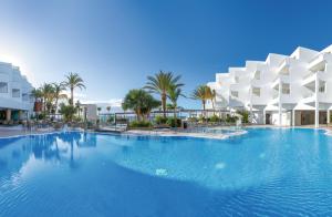 甘迪亚海滩Hotel Riu Palace Jandia的一座棕榈树和建筑的大型游泳池