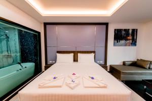 北芭堤雅The Proud Hotel Pattaya - SHA Certified的一间卧室配有一张床和一个浴缸,另一间卧室配有两张毛巾
