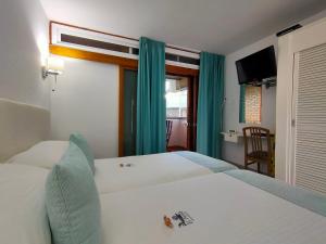 英格兰海滩厄尔帕西奥公寓的一间卧室配有白色的床和蓝色窗帘