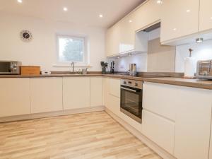 卡姆尔福德Lily Cottage的厨房铺有木地板,配有白色橱柜。