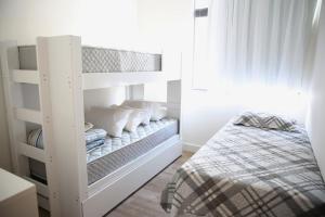 迪亚曼蒂纳Apartamento Premium的白色的客房内的一张白色双层床,配有一张床
