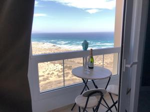 科斯塔卡玛Apart. Playa La Barca的阳台上的桌子上放着一瓶葡萄酒