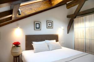 AulestiaCasa Rural Andikoetxe Landetxea的一间卧室配有白色床单和木制天花板。