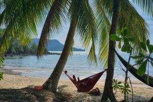 瓜隆岛孤独海滩旅馆的海滩上两棵棕榈树之间的吊床