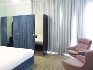 麦纳麦东方皇宫酒店的酒店客房配有一张床、两把椅子和镜子