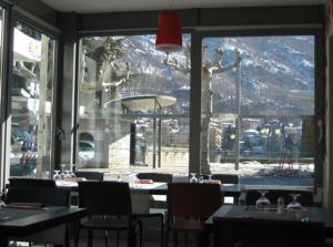 奥梅尼亚Albergo Ristorante Pomodoro的餐厅设有桌椅和大窗户。