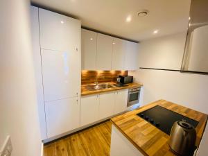 切尔滕纳姆Stewart St James Walk Apartment的厨房配有白色橱柜和木桌