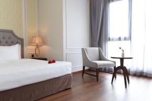 金瓯Phu Cuong Hotel Ca Mau的一间卧室配有一张床、一把椅子和一张桌子
