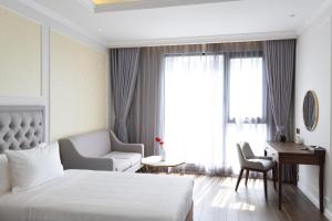 金瓯Phu Cuong Hotel Ca Mau的酒店客房配有一张床、一把椅子和一张书桌