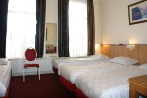 阿姆斯特丹维斯特图伦酒店的酒店客房,设有两张床和一张红色椅子