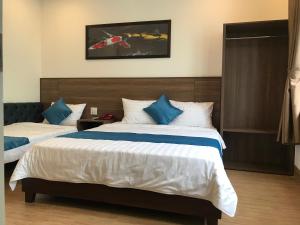 归仁Hotel Hoàng Hưng Quy Nhơn的一间卧室配有两张带蓝白色枕头的床