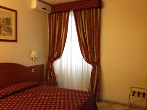 罗马芝加哥酒店的一间卧室配有床和带窗帘的窗户