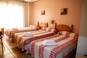 洛斯阿尔卡萨雷斯伊尔科尔多贝斯膳食公寓的配有红色和白色毯子的客房内的三张床