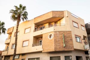 洛斯阿尔卡萨雷斯伊尔科尔多贝斯膳食公寓的前面有棕榈树的建筑