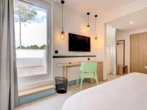 居让梅斯特拉ibis Styles Arcachon Gujan Mestras的一间卧室配有一张床、一张书桌和一个窗户。