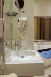 利雅德Coupard Hotel的浴室水槽和镜子旁的吹风机