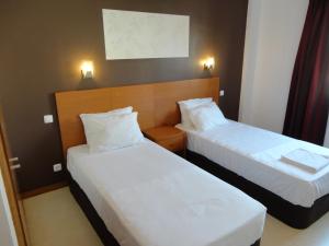 罗安达罗安达酒店的配有白色床单的酒店客房内的两张床