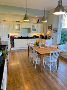切尔滕纳姆Laurel House的厨房配有木桌和白色橱柜。