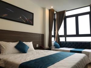 归仁Hotel Hoàng Hưng Quy Nhơn的酒店客房设有两张床和大窗户。