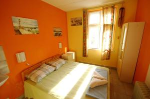 瓦尔纳哟嗬旅舍的一间卧室设有橙色的墙壁和一张带窗户的床