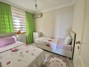 特拉布宗Trabzon Seaside的客房设有两张床和一个带绿色窗帘的窗户。
