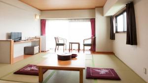 草津新柯约酒店的一间带桌子的客厅和一间带窗户的房间