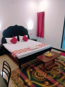 乌代浦Amritchandra homestay and hostel的一间卧室配有一张带红色枕头的床和一张桌子