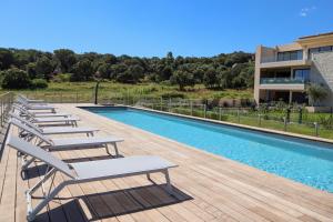 维琪奥港CALADEA Locations de Vacances 5 étoiles, piscine chauffée的游泳池旁的一排躺椅