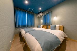 富士河口湖02 Resort Club -蒼SOU-的一间卧室设有两张床和蓝色窗帘