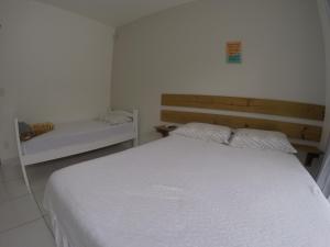 弗洛里亚诺波利斯Florianópolis Pousada Moçambeach的卧室配有白色的床和长凳