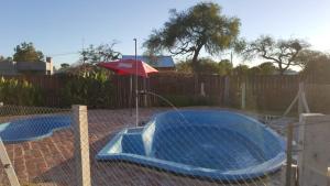 GualeguaychúCabañas Diamante的一个带遮阳伞的游泳池,位于围栏旁