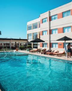 特尔马斯德里奥翁多Hotel Termal Los Cardones & Spa的大楼前的游泳池配有椅子和遮阳伞