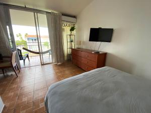 多拉多多拉多帕拉蒂姆别墅的一间卧室配有一张床、一台电视和一个阳台