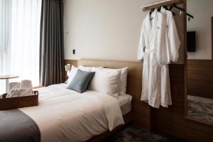 釜山Sangsang Stay Busan的酒店客房设有一张床和挂在墙上的长袍