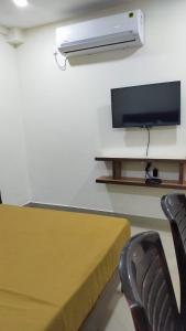 门格洛尔Bhumi Residency的配有电视和桌椅的房间