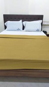 门格洛尔Bhumi Residency的一张黄色的床,上面有两个枕头