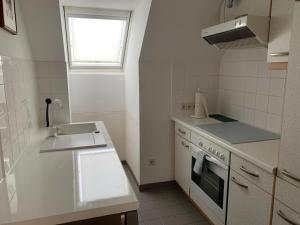 巴登Amadeus Apartment的白色的厨房设有水槽和炉灶。