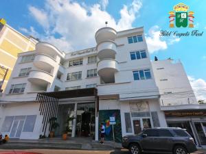 弗洛伦西亚Hotel Caquetá Real HSC的前面有一辆汽车停放的白色建筑