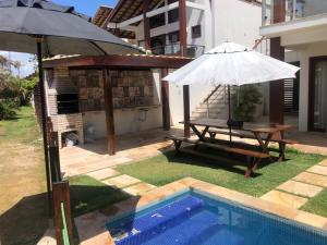 泰巴Casa Taíba Beach Resort的一个带桌子和遮阳伞的庭院,毗邻一个游泳池