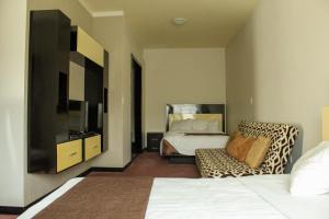 底拉斯卡拉坎卡利商务套房酒店的一间卧室配有一张床、一台电视和一把椅子