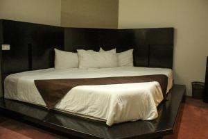 底拉斯卡拉坎卡利商务套房酒店的一间卧室配有一张大床和黑色床头板